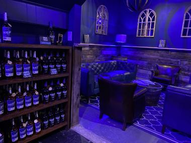speakeasy styled tasting room at blue note bourbon bottles on shelves for sale with lounge area