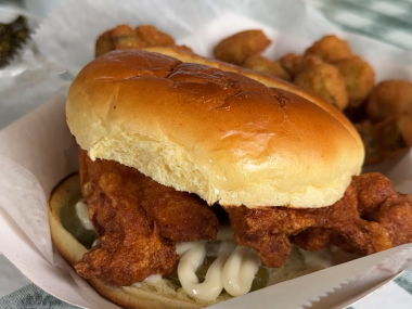 fried chicken sandwich in plate on top of green and white tablecloth