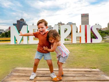 two children on Mud Island River Park pose in front of large Memphis letters