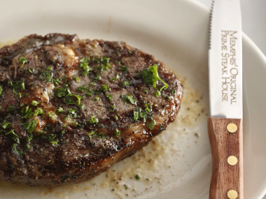 well seasoned steak on plate next to steak knife