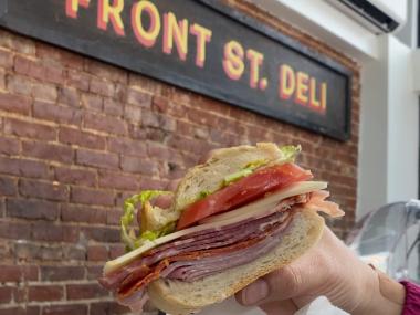 italiano sub held up to sign of Front St Deli