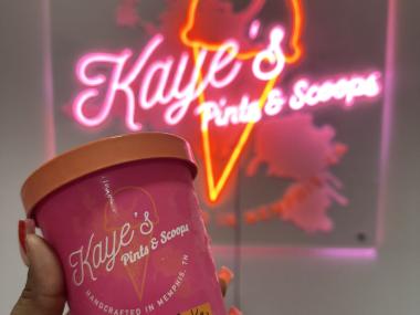 holding carrot spice cake in front of neon sign