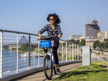 woman rides along riverfront on bike