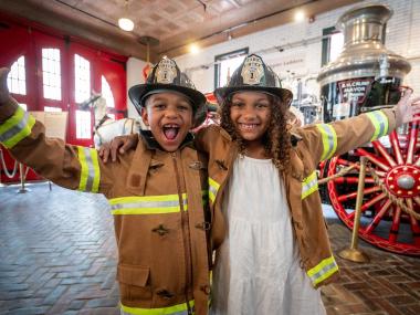 Two children dressed as firefighters at the Fire Museum of Memphis.