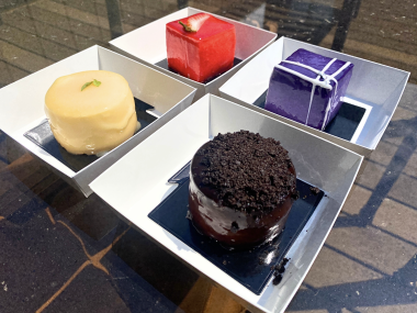 four mini cheesecakes decorated in different colors, shapes, and designs