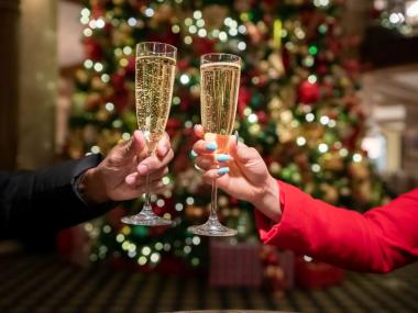 woman and man holding champagne glasses by Christmas tree