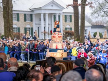 elvis birthday celebration with people crowding around a huge birthday cake at graceland