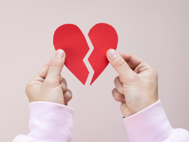hands holding up two sides of a broken heart