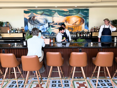 Man sits at bar at Bar Liminia while bartenders work behind it