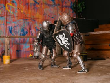 two people in knight armor battle with swords and shields