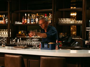 BARTENDER pours a drink behind bar at The Dame
