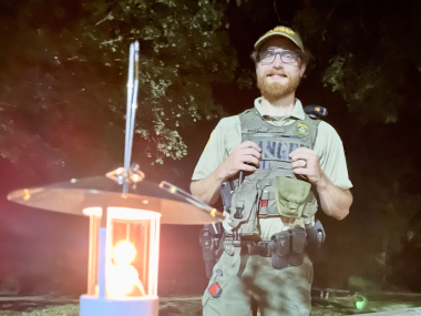 ranger smiles for photo with lantern lit in front of him