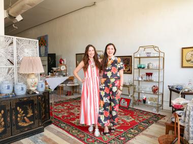 Two women standing next to each other surrounded by antiques