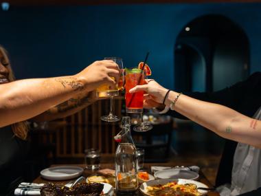 Friends raising glasses, we just see arms extended with glasses cheersing