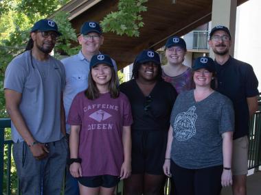 a group of people standing together smiling wearing matching navy baseball caps