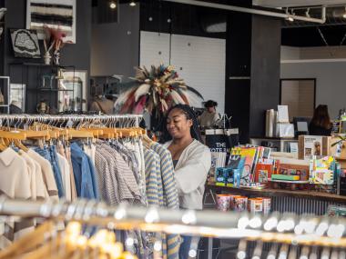 Girl shopping and sorting through clothing racks at a store