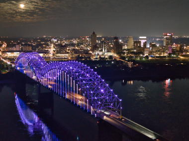 Memphis bridge lit up purple with city skyline in background