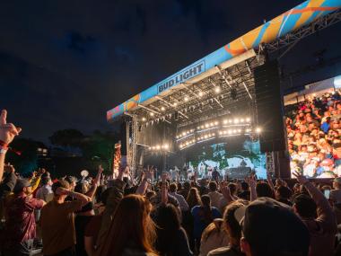Crowd watching a performer on stage at night at RiverBeat Music Festival.