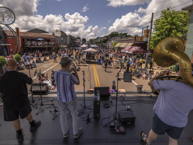 band plays on stage overlooking crowd at Overton Square Crawfish Festival