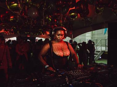 African American Woman Djing, wearing headphones with black fishnext top and black corset